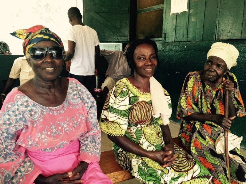 Esther, a woman who has cataracts, sits with her two friends in Liberia.