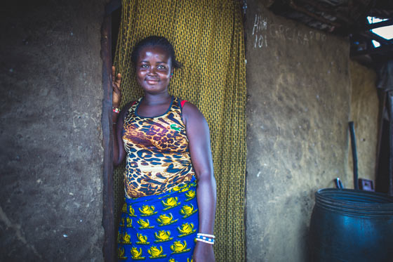 Kadiatu, a resident in Liberia’s, smiling and standing at the door of her home