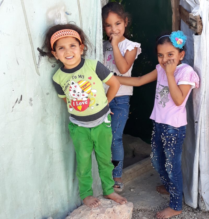 Syrian Refugee girls laughing in the doorway of their home in Lebanon