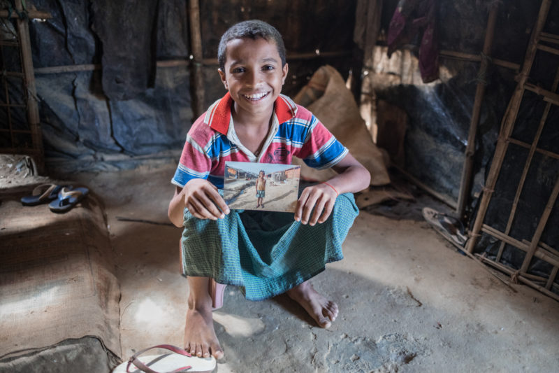 Harun, a Rohingya Refugee, holding a photo of himself from a year earlier